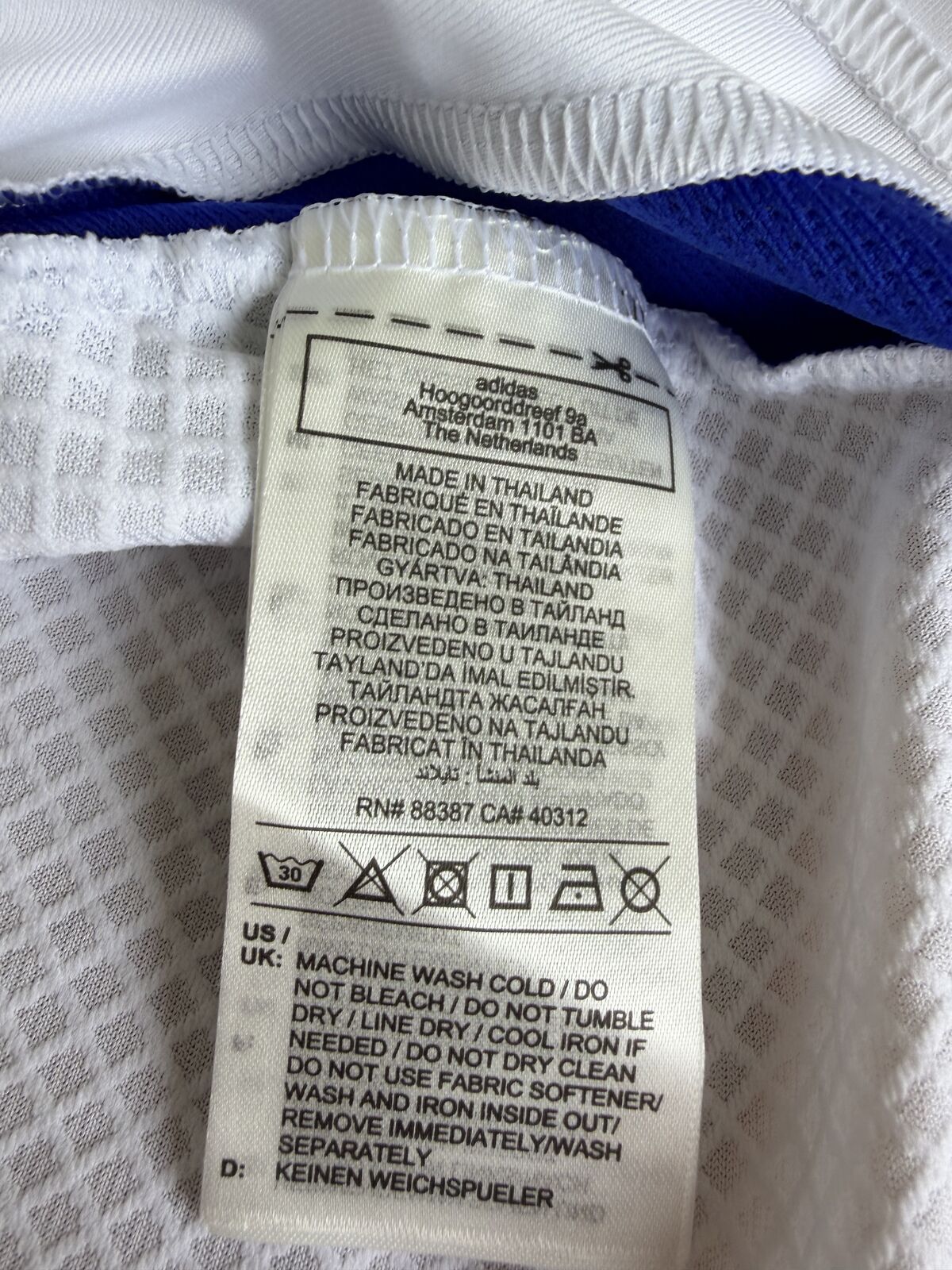 Interior care label showing the adidas Amsterdam address, Made in Thailand in twelve languages, RN and CA numbers and wash symbols