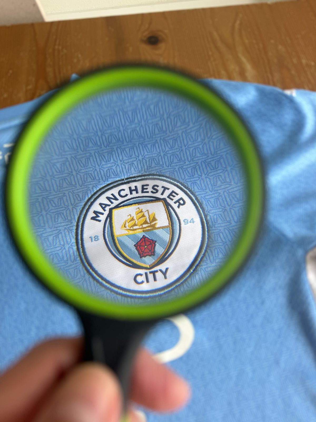 Manchester City crest viewed through a magnifying glass