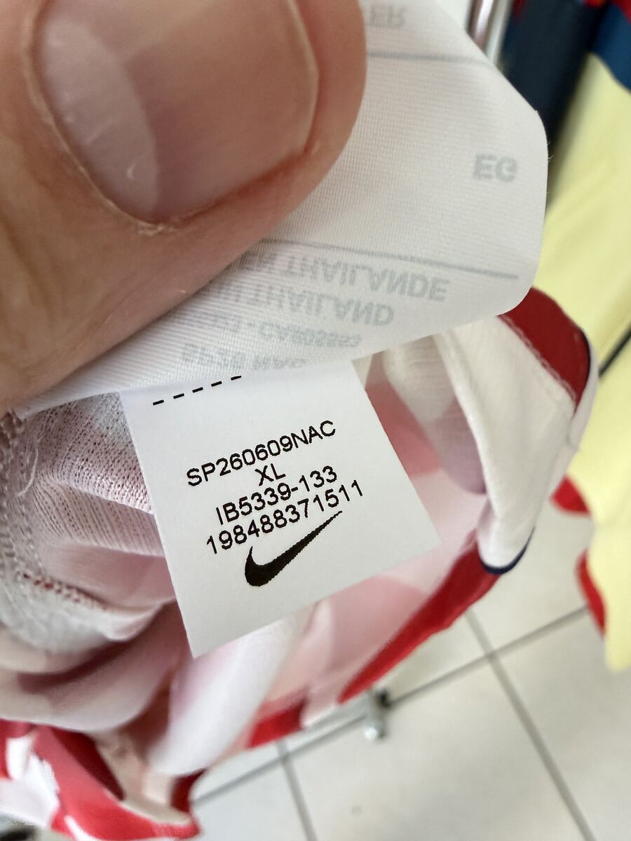 Genuine Nike neckline tag showing style code SP260609NAC, size XL, IB5339-133, and UPC number above a crisp black swoosh